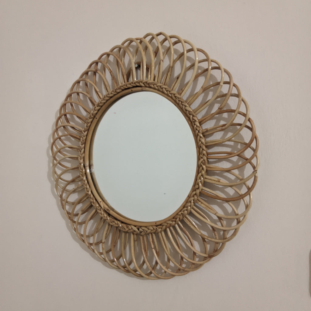 Round woven mirror on a plain wall