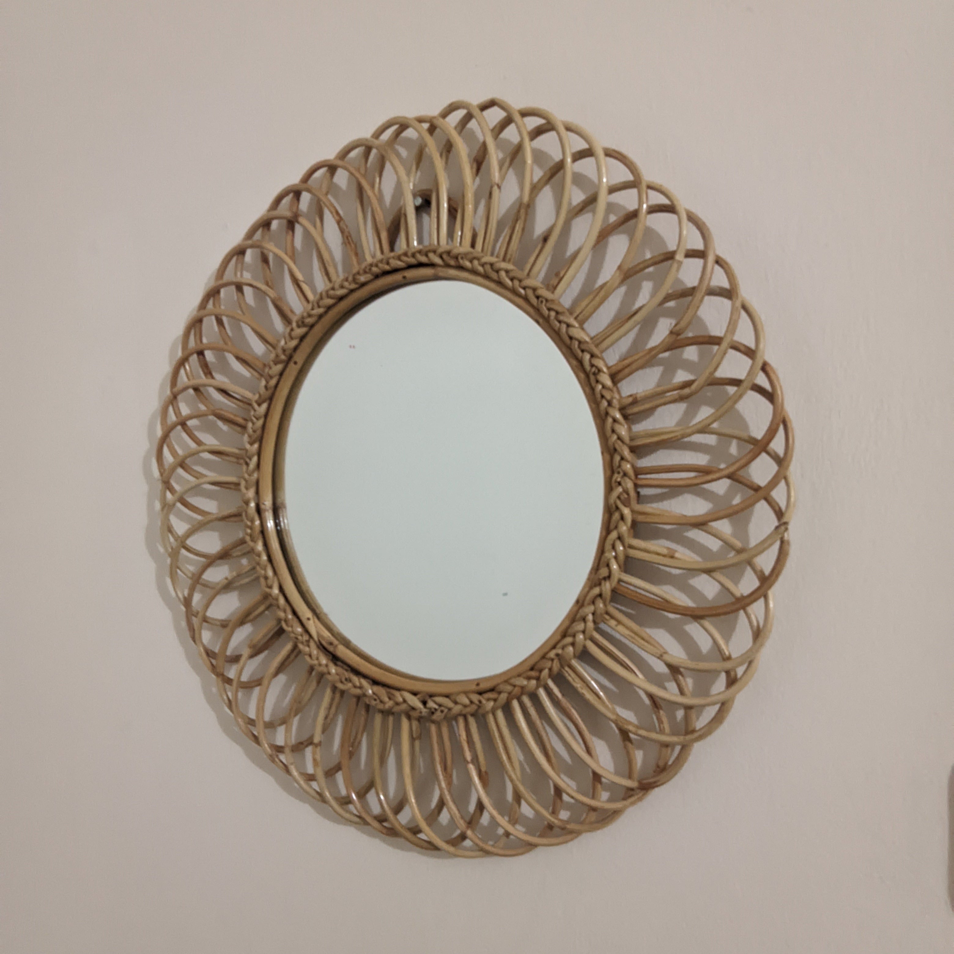 Round woven mirror on a plain wall