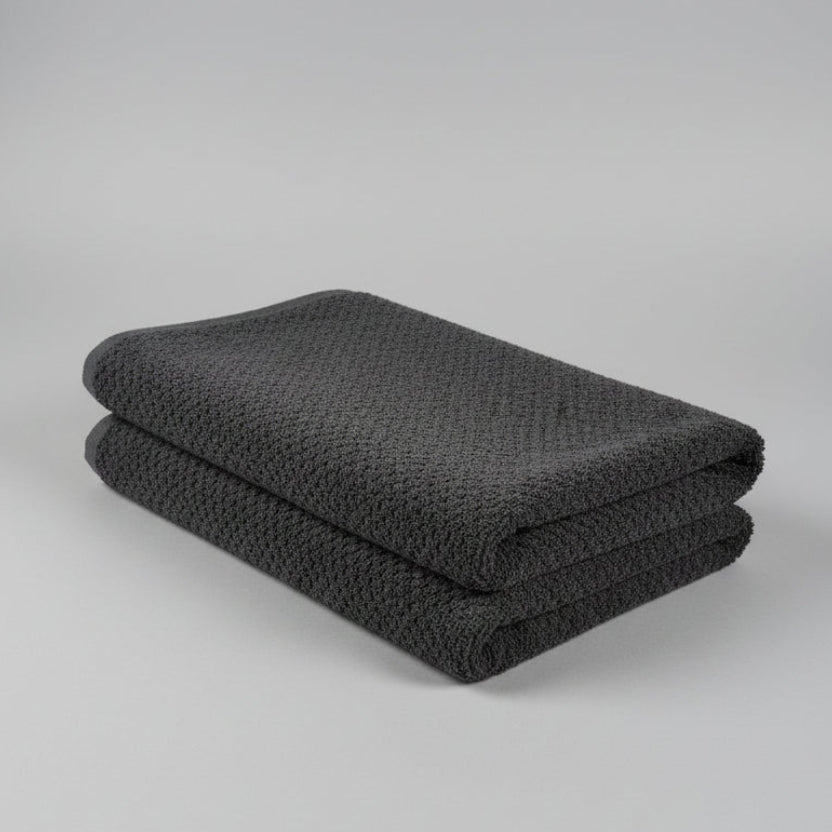 Folded dark gray blanket on a white surface