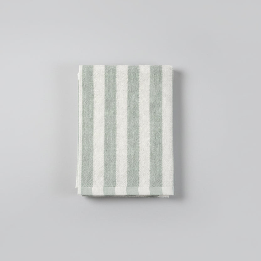 Striped towel with green and white stripes on a dark surface