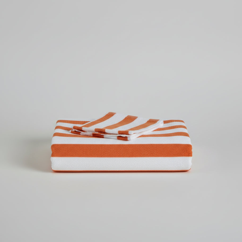 Striped towel with orange, white, and gray colors on a tiled floor.