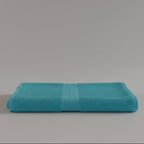Turquoise towel folded on a light gray background