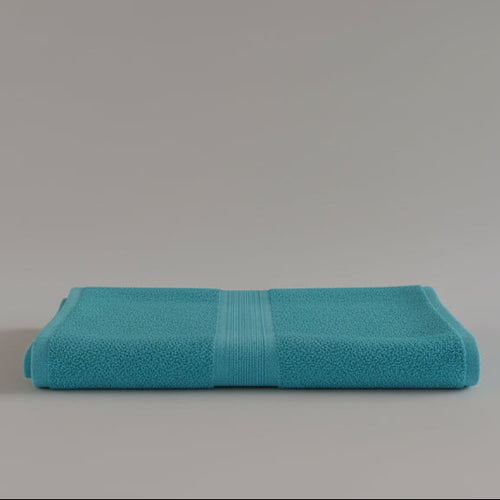 Turquoise towel folded on a light gray background