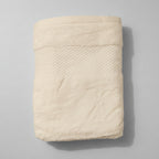 Folded white towel on a pink textured surface