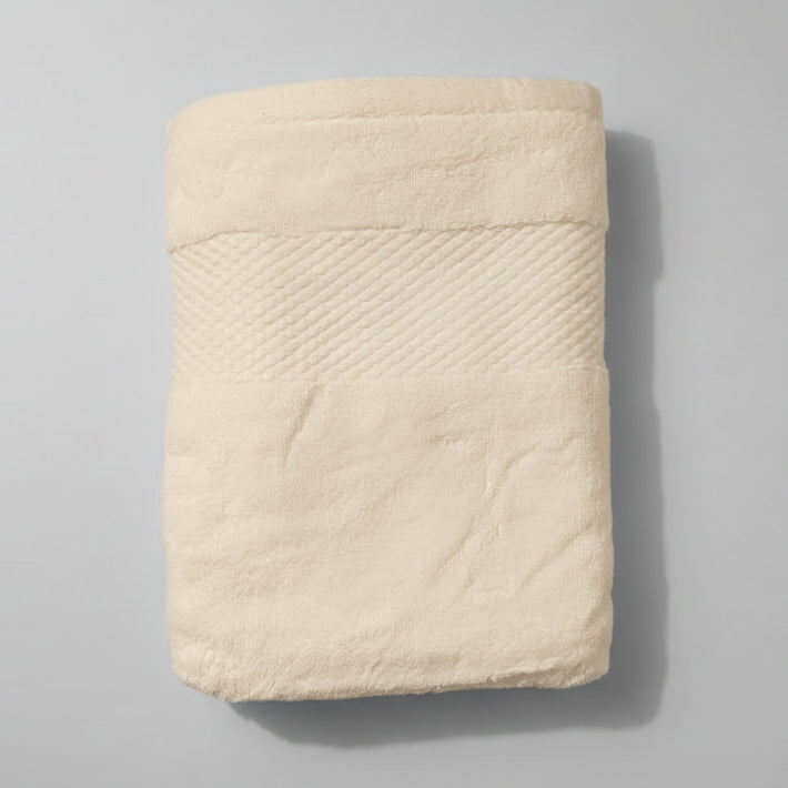 Folded white towel on a pink textured surface