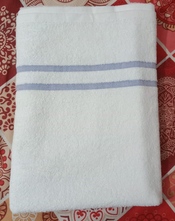 White towel with blue stripes on a red patterned fabric background