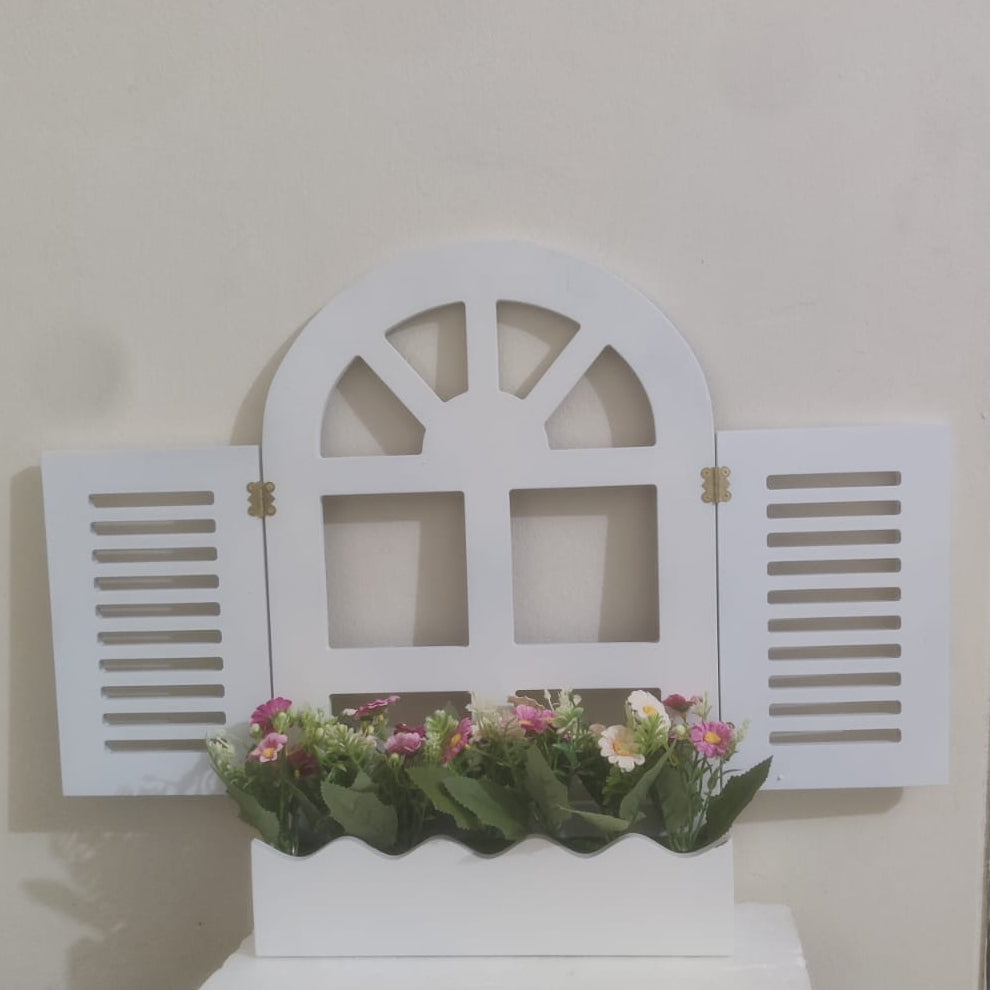 Decorative white window frame with flowers on a shelf against a beige wall.